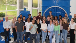 Course students visiting AVK, standing in front of a flanged valve measuring several meters in diameter